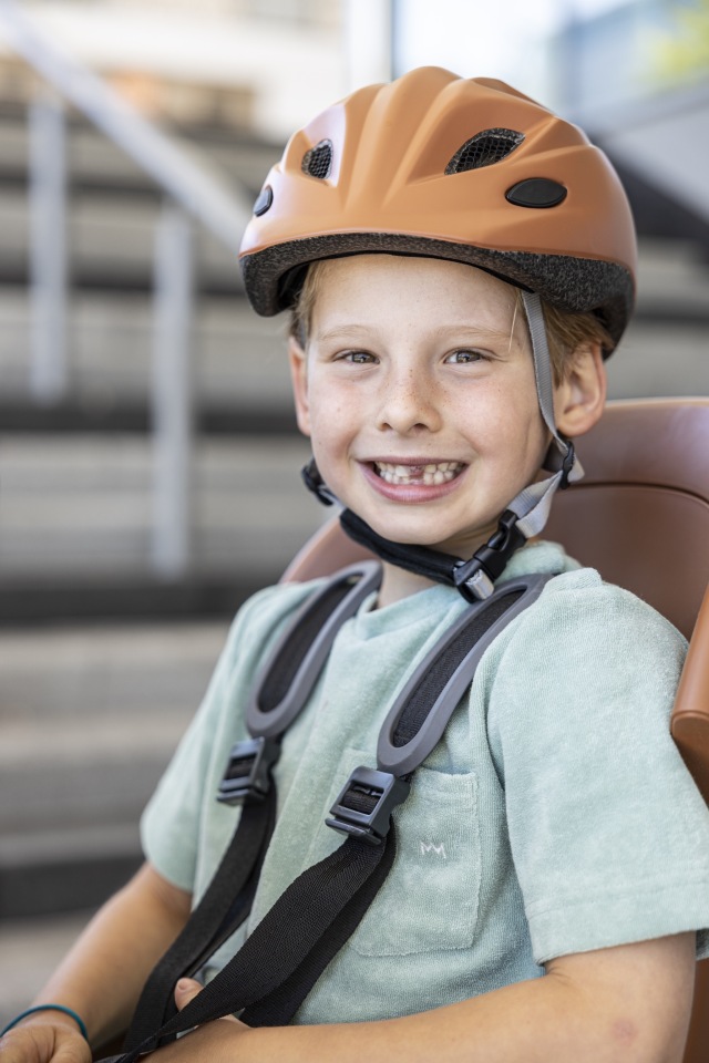 kind met oranje fietshelm op
